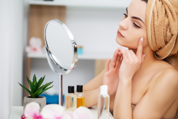 Donna che si prepara per il lavoro facendo il trucco mattutino nello specchio del bagno a casa.