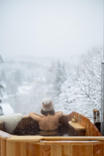 Donna che si rilassa in un bagno caldo sulle montagne innevate