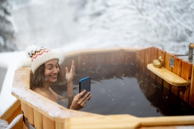 Donna che si rilassa in un bagno caldo sulle montagne innevate