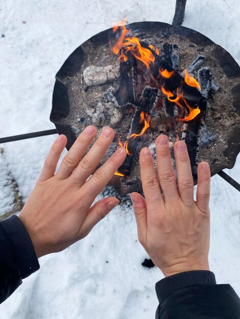 Donna che si scalda le mani vicino al pozzo del fuoco durante la fredda giornata invernale