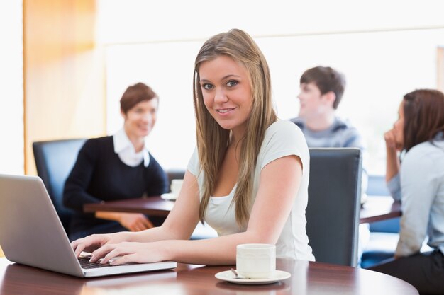 Donna che si siede alla caffetteria al tavolo utilizzando il computer portatile