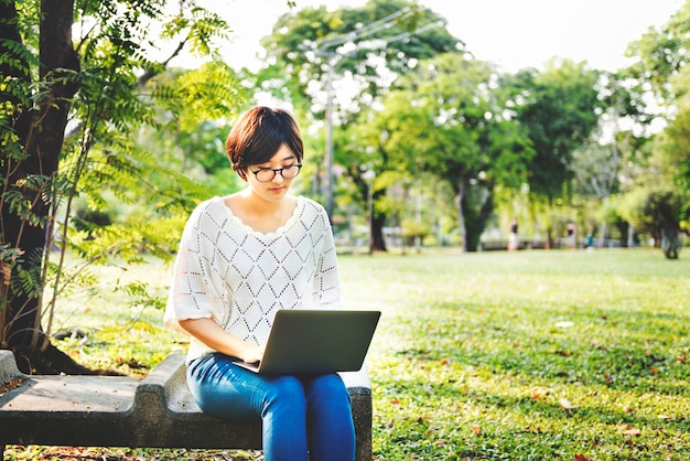 Donna che si siede concetto di battitura a macchina del parco del computer portatile