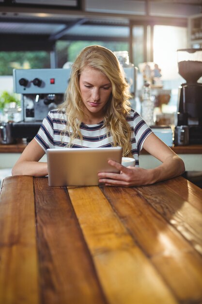 Donna che si siede in un caffè facendo uso della compressa digitale