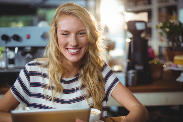 Donna che si siede in un caffè facendo uso della compressa digitale