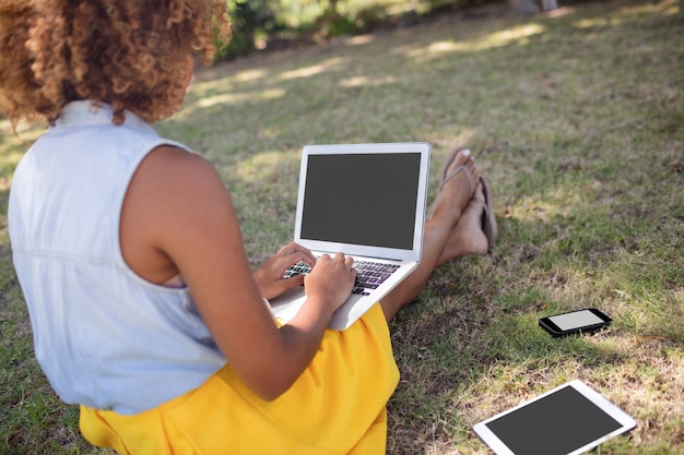 Donna che si siede nel parco e che utilizza computer portatile