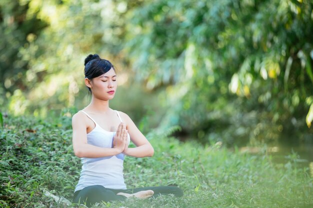 Donna che si siede nell&#39;yoga in prato inglese - rilassi in natura