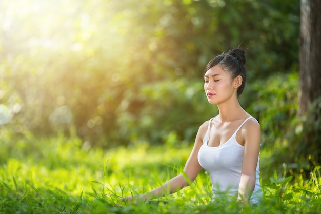 Donna che si siede nell&#39;yoga in prato-- rilassi in natura felicità femminile.