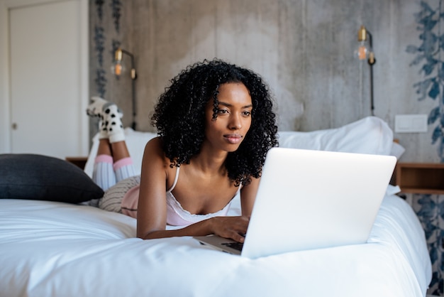 Donna che si siede sul letto sul computer