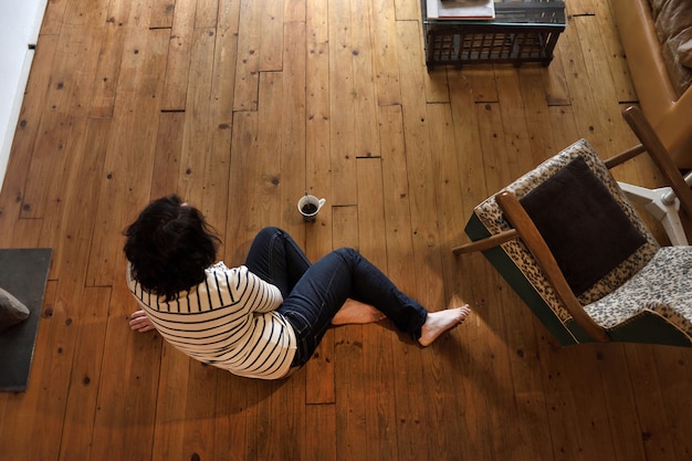 Donna che si siede sul pavimento di legno