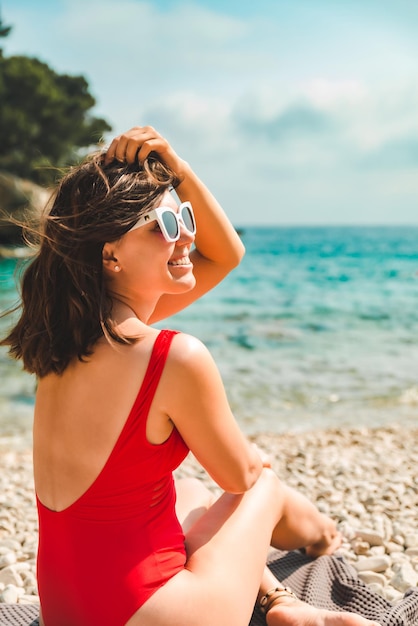 Donna che si siede sulla coperta al concetto di vacanza estiva della spiaggia del mare