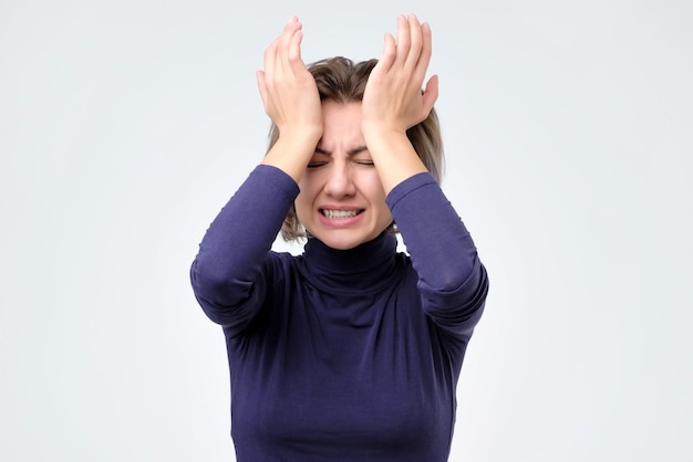 Donna che si tocca la testa con la mano e fa la faccia arrabbiata mentre si trova in studio