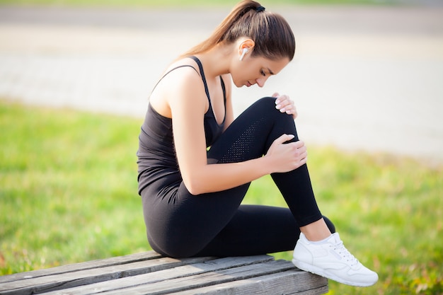 Donna che soffre dal dolore alla gamba dopo l'allenamento