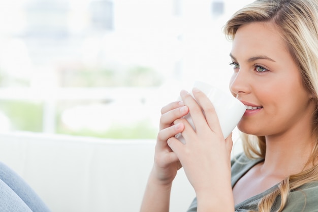 Donna che sorride con la coppa tenuta alle labbra e le ginocchia sollevate