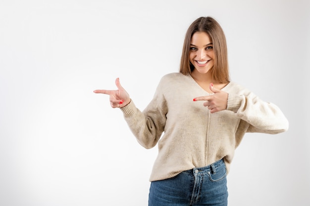 Donna che sorride e che indica al copyspace isolato sopra bianco