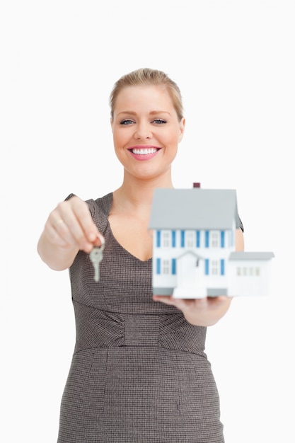 Donna che sorride mostrando una casa modello e una chiave