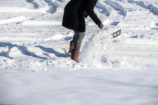 Donna che spala la neve per liberare il suo vialetto dopo la tempesta invernale