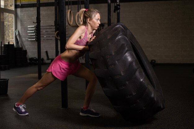 Donna che spinge pneumatico in palestra