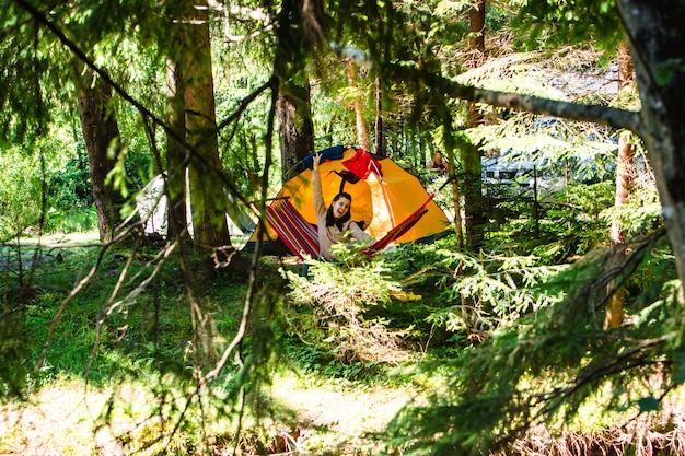 Donna che stabilisce in amaca nella tenda della foresta sullo sfondo