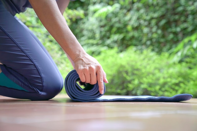 Donna che stende il tappetino per esercizi Concetto di stile di vita sano