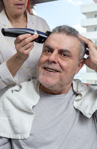 Donna che taglia i capelli di un uomo a casa