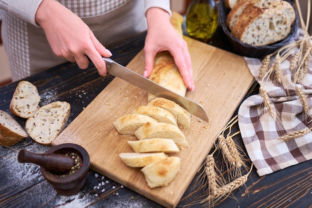 Donna che taglia il pane appena sfornato al tavolo da cucina in legno