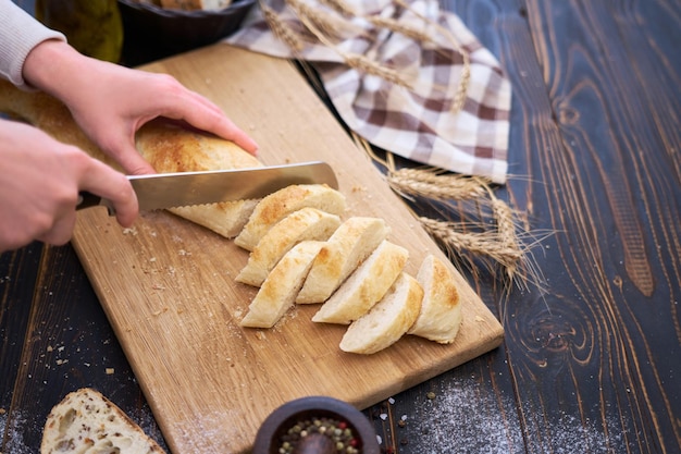 Donna che taglia il pane appena sfornato al tavolo da cucina in legno