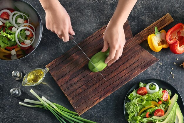 Donna che taglia l'avocado per una gustosa insalata di verdure sul tavolo