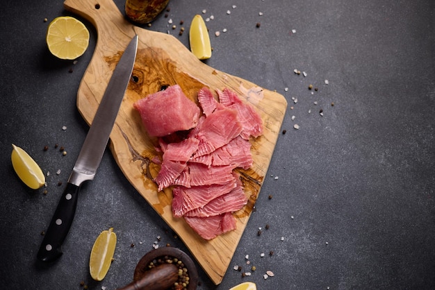 Donna che taglia la bistecca di tonno in fette su un taglio di legno in una cucina domestica che cucina tonno