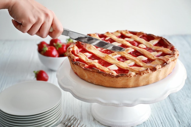 Donna che taglia la torta di fragole sul tavolo