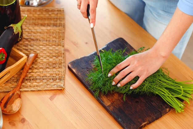 Donna che taglia prezzemolo su tavola di legno in cucina