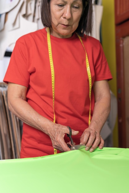 Donna che taglia vestiti su un tavolo da taglio in un'officina tessile