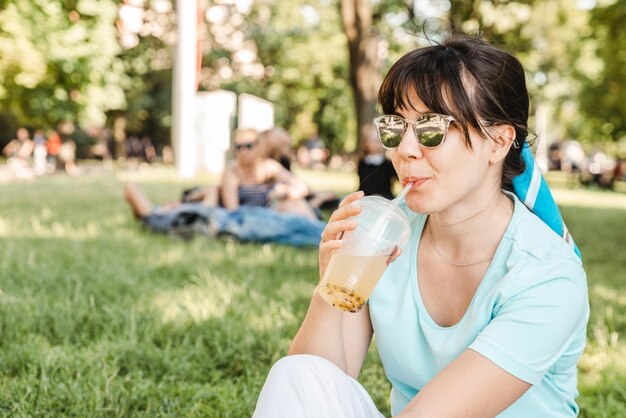 Donna che tiene bevanda fresca nel parco cittadino sfocato sfondo