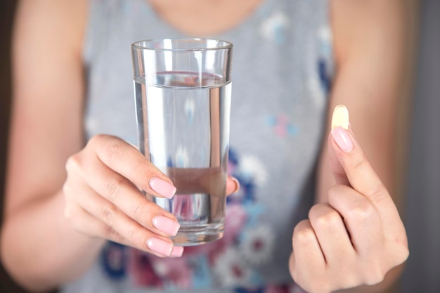 Donna che tiene bicchiere d'acqua e droga