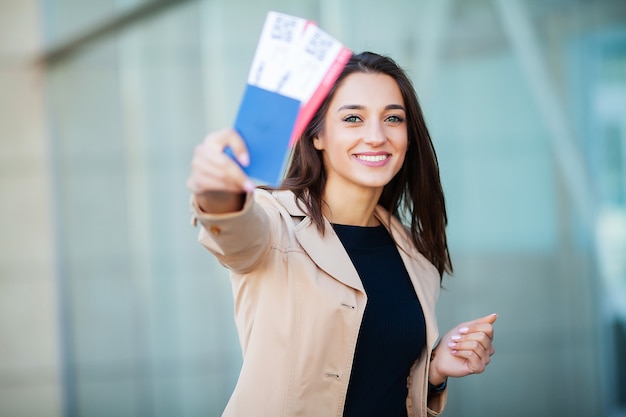 Donna che tiene due biglietti aerei nel passaporto all'estero vicino all'aeroporto