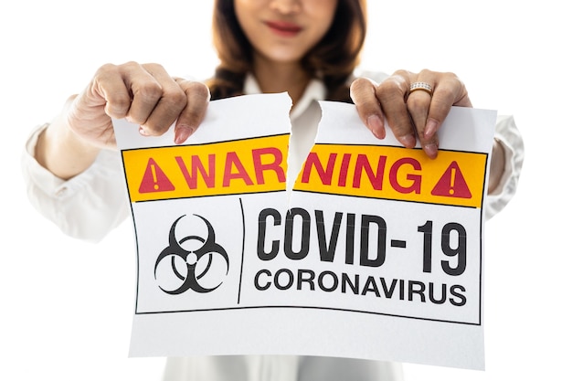 Donna che tiene e strappa la carta con le parole di avvertimento del coronavirus Covid-19. L'idea o il concetto per la fine, la felicità, la libertà e il benessere dopo aver terminato e recuperato da Coronarivus.