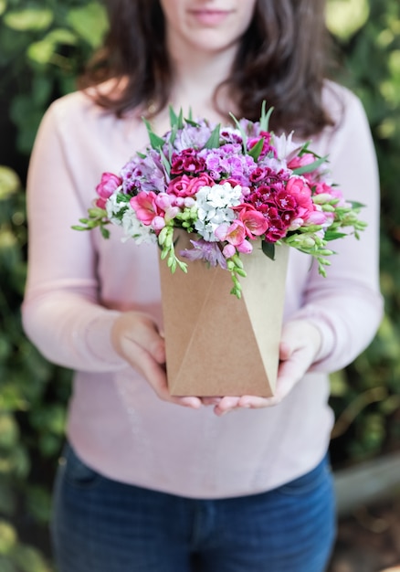 Donna che tiene i fiori rosa in un vaso