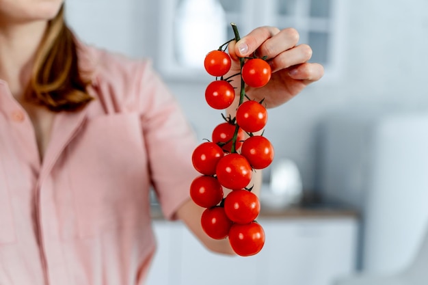 Donna che tiene i pomodorini maturi nelle mani Sfondo della cucina Immagine ritagliata Cibo sano