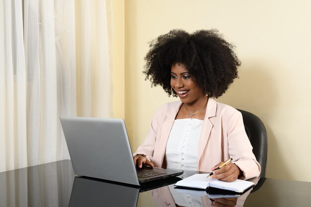 donna che tiene il computer portatile durante la digitazione sulla tastiera, giovane donna afro