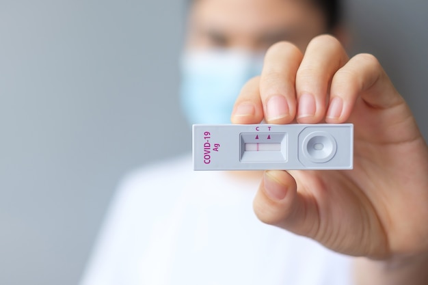 Donna che tiene il kit di test rapido dell'antigene con risultato negativo durante il test del tampone COVID-19. Coronavirus Self nasale o Home test, concetto di blocco e isolamento domestico