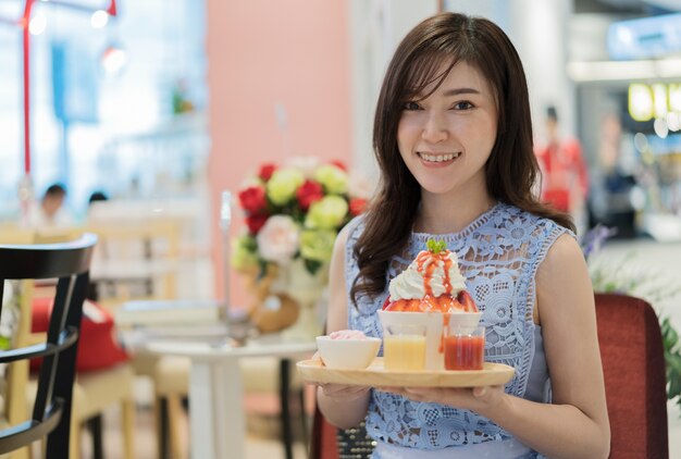 donna che tiene il latte fresco rasato di ghiaccio o fragola bingsu