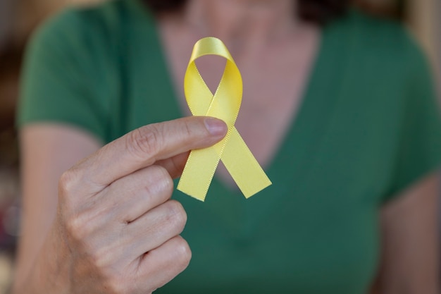 Donna che tiene il nastro giallo della campagna di prevenzione del suicidio. Settembre giallo.