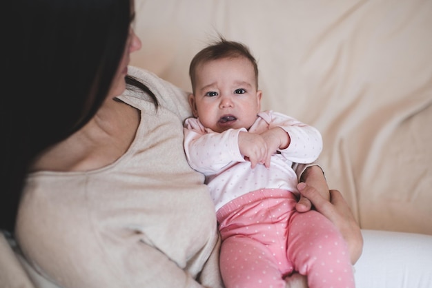 Donna che tiene il pigiama da bambino sdraiato sulla mano della madre che piange Una bambina triste ha le coliche