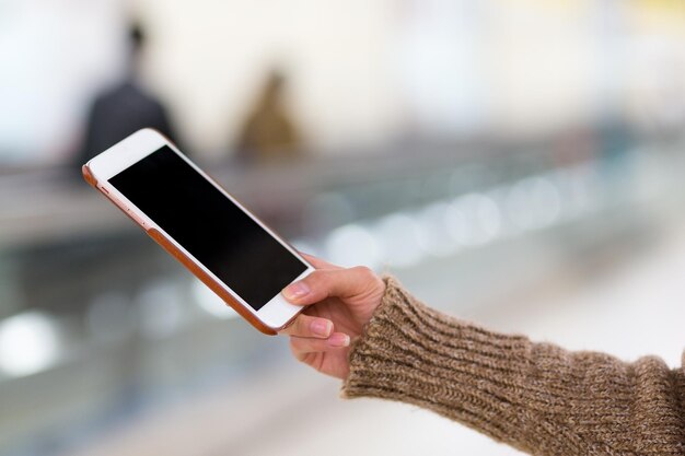 Donna che tiene il telefono cellulare alla stazione ferroviaria