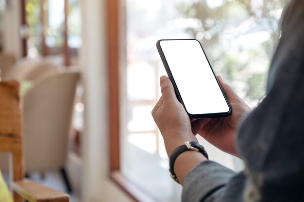donna che tiene il telefono cellulare nero con lo schermo del desktop vuoto nella caffetteria
