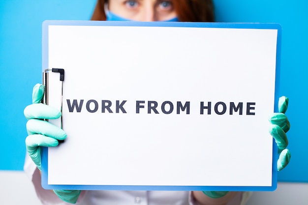 Donna che tiene in bianco con il lavoro dell'iscrizione dalla casa che richiede la fermata di diffusione covid-19.