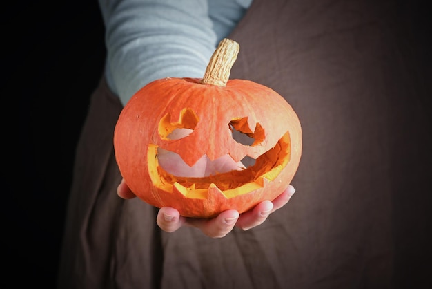 Donna che tiene in mano fresca zucca primo piano Carving A Pumpkin For Halloween