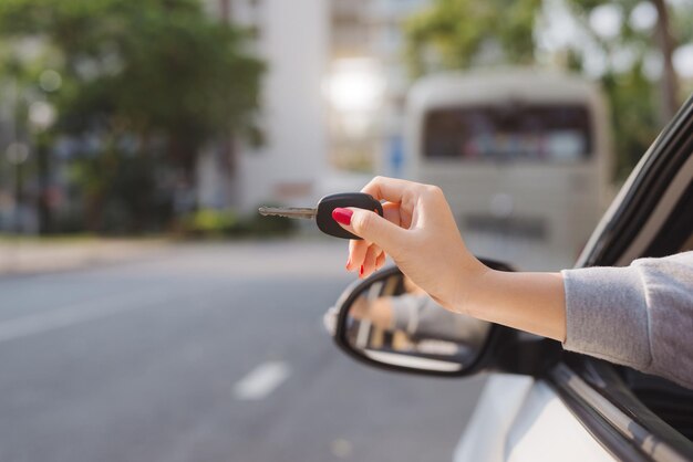 Donna che tiene in mano le chiavi di accensione di un'auto e le fa dondolare attraverso il finestrino laterale aperto