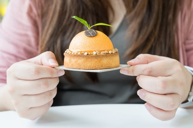 Donna che tiene la torta di forma arancione minima.