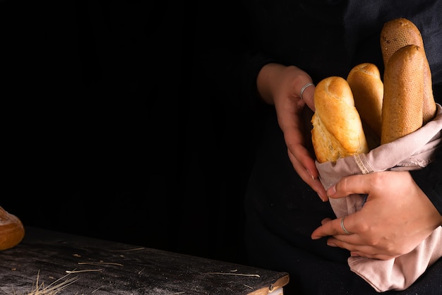 Donna che tiene le specie saporite del pane fresco su un&#39;oscurità
