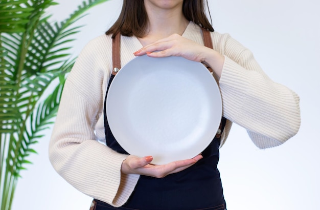 Donna che tiene piatto di porcellana con la mano su sfondo bianco